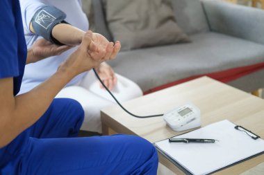 Evde sağlık hizmeti konsepti. Ev ziyareti sırasında kan basıncını ölçen sağlık görevlisi.. 