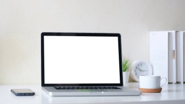 Comfortable home office. Laptop computer, stationery and potted plant on white table.	