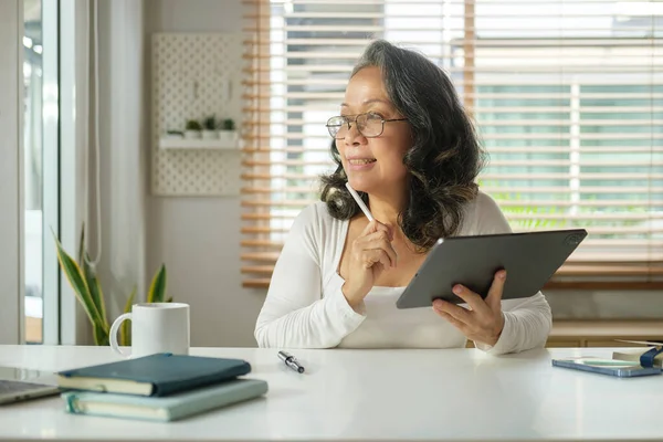 Mulher Madura Cuidadosa Segurando Tablet Digital Olhando Para Longe Pensando — Fotografia de Stock