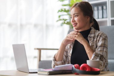 Laptop kullanan, düşünen, hayal kuran ve evde sakin vakit geçiren güzel bir kadın..