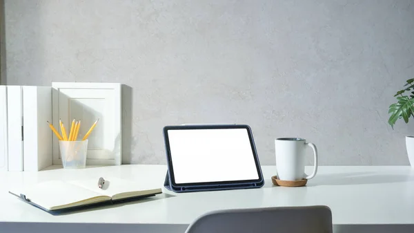 白色桌子上装有空白屏幕 咖啡杯 文具和相框的数码平板电脑 — 图库照片