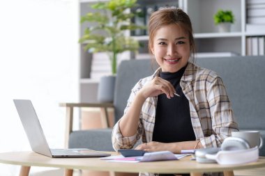 Gülümseyen Asyalı ev kadınının portresi dizüstü bilgisayar kullanıyor, ev bütçesini yönetiyor ya da ev giderlerini karşılıyor..