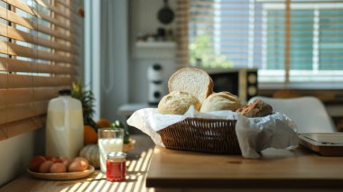 Taze pişmiş ekmek, sağlıklı kahvaltı için mutfak tezgahında çilek reçelli bir bardak süt..