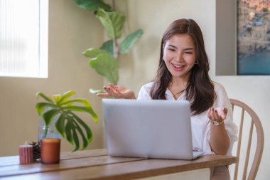 Güzel genç bir kadın, uzaktan eğitim için dizüstü bilgisayar kullanıyor. Konforlu ev içi internet iletişimi..