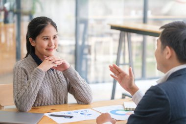 Gülümseyen çeşitli meslektaşlar toplantı odasında toplanmış mali istatistikleri tartışıyorlar. Çok ırklı iş arkadaşları ofis toplantısında işbirliği yaparken ve takım çalışması yaparken eğleniyorlar.