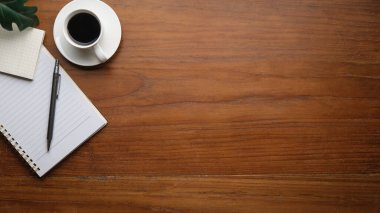 Top view of coffee, sticky note, notebook and pen on wooden table. Copy space for your text.	