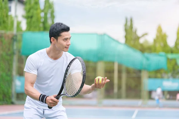 Handsome male tennis player with racket and ball preparing to serve at beginning of game or match.