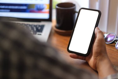 Close up over shoulder businessman using mobile phone at office desk.	