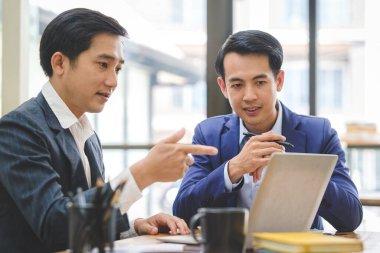 Bir grup genç iş adamı toplantı odasında beyin fırtınası yapıyor ve iş stratejilerini tartışıyorlar..