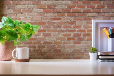 Bir fincan kahve, saksı ve beyaz masanın üzerinde boş resim çerçevesi olan ofis masası..