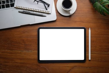 Düz yerde, boş ekranlı dijital tabletin üst görüntüsü, dizüstü bilgisayar, defter ve kahve fincanı ahşap masada.. 