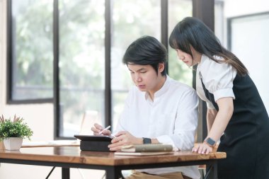 Dijital tablet kullanan genç girişimci işadamları, birlikte çalışma alanında yeni bir projede işbirliği yapıyorlar.