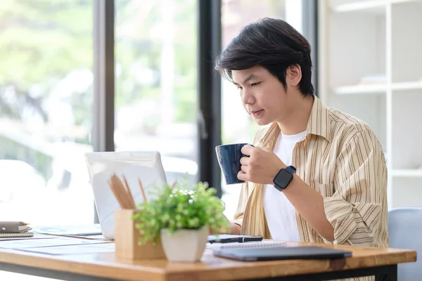 아시아인 프리랜서가 커피를 마시고 노트북으로 이메일읽는 — 스톡 사진