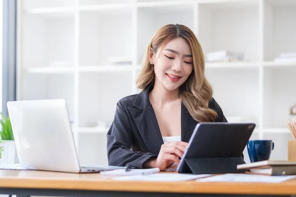 迷人的亚洲女企业家坐在现代办公室的办公桌前 使用数码平板电脑 — 图库照片