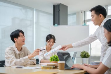 İş arkadaşları finansal verileri tartışıyor, birlikte parlak işyerlerinde çalışıyorlar.