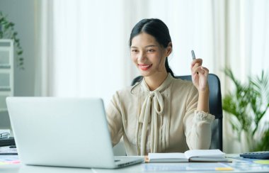 Çalışan masadaki dizüstü bilgisayarda e-posta okuyan çekici genç iş kadını..