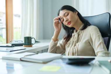 Ofis masasında oturan stresli genç iş kadını..