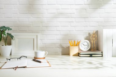 Resim çerçeveli yaratıcı tasarımcı çalışma alanı beyaz masa üzerinde kırtasiye ve saksı bitkisi oluşturur.