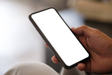 Boş ekranlı akıllı telefonu tutan ellerin yakın görüntüsü ve reklam veya metin iletiniz için boş alanı olan sol taraf.
