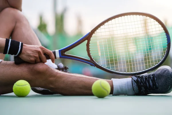 stock image Man tennis player in sportive clothes sitting on the court, resting after game or training.
