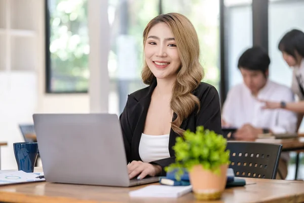 美丽的年轻亚洲女人在明亮的现代办公室里与计算机打交道 — 图库照片