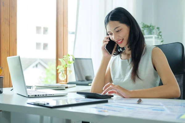 微笑的女企业家坐在明亮的现代化办公室里 用手机交谈 — 图库照片