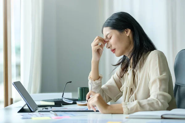 Stressed female employee feeling tired at work, suffering from headache, stress at work or migraine.