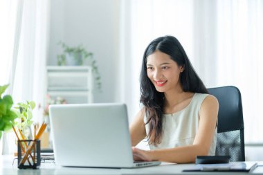 İş yerinde dizüstü bilgisayar kullanan çekici genç bir iş kadını..