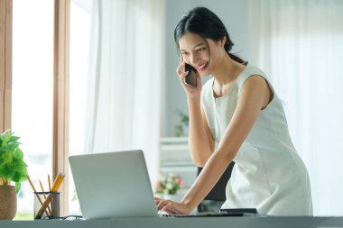 Attractive asian businesswoman talking with her business partner while sitting in modern office.	