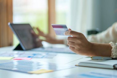 Güzel Asyalı kadın kredi kartı tutuyor ve bilgisayar kullanıyor. İnternet alışverişi, e-ticaret, internet bankacılığı kavramı.