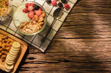 Tahta masada sağlıklı kahvaltı için meyveli yoğurt. Boşluğu olan üst görünüm.