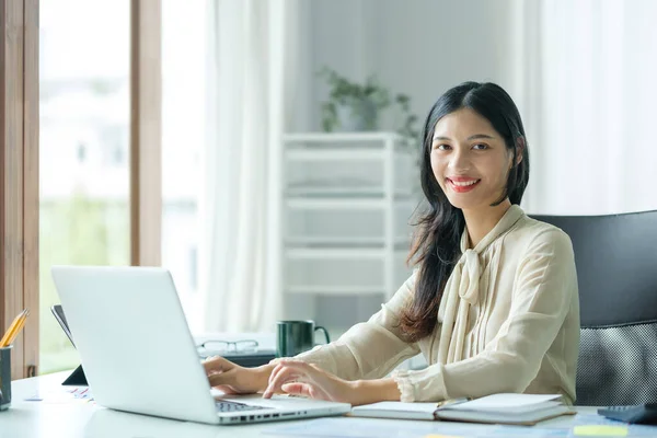 Asyalı Kadını Ofisinde Oturuyor Kameraya Gülümsüyor — Stok fotoğraf