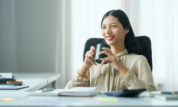 快乐的年轻女商人坐在舒适的办公椅上 享受着早晨的咖啡 — 图库照片