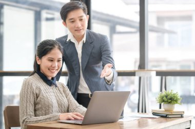 Dost canlısı iş adamları dizüstü bilgisayar kullanıyor, modern ofiste yeni bir proje üzerinde birlikte çalışıyorlar..