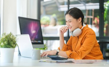 Çalışan masadaki dizüstü bilgisayarda e-posta okuyan çekici genç iş kadını..