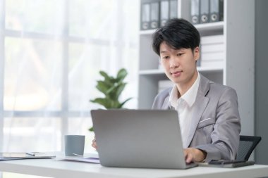 Businessman using laptop computer at desk in modern workplace.	