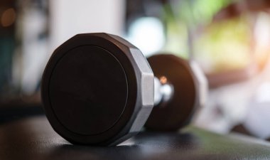 Spor salonunun arka planında bulanık bir dambıl. Fitness için spor aletleri.