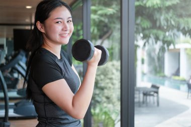 Güzel Asyalı kadın dambılla egzersiz yapıyor..