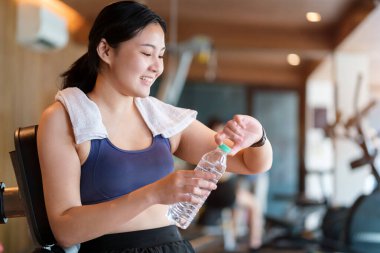 Tatmin olmuş sporcu kadın elinde su şişesi tutuyor fitness takip cihazını kontrol ediyor spor yapıyor ya da vücut fonksiyonlarını kontrol ediyor..