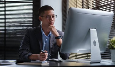 Handsome young businessman working with computer at office.	