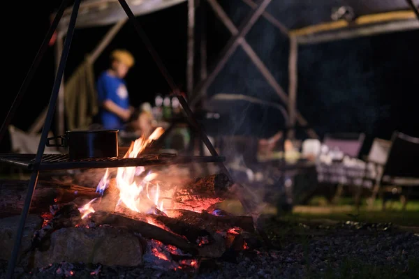 Cooking pot over bonfire at touristic camp at night. Camping, recreation, outdoor activities concept.