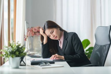 Ofis masasında oturan stresli genç iş kadını..
