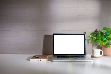 Bilgisayarı, kahve fincanı, saksı bitkisi ve kırtasiyesi olan ofis masası. Reklam metniniz için boş ekran.