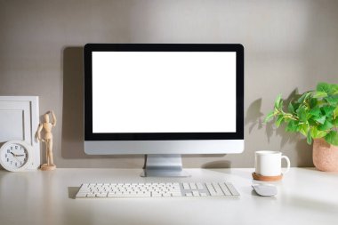 Beyaz ekran bilgisayarı ve ofis malzemeleri beyaz masada..