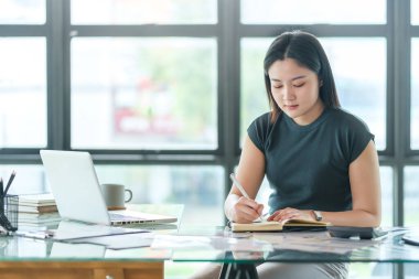 Genç bir bayan yönetici asistanı iş planlarını not alıyor. Ofisinde bilgi topluyor..