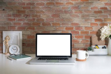 İçişleri Bakanlığı. Bilgisayar dizüstü, resim çerçevesi, kahve fincanı, defter ve çiçek saksısı beyaz masada..