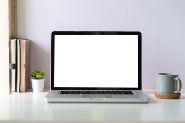 Dizüstü bilgisayarı, kahve fincanı ve kitapları olan beyaz çalışma masası. Modern çalışma alanı, reklam metniniz için boş ekran.