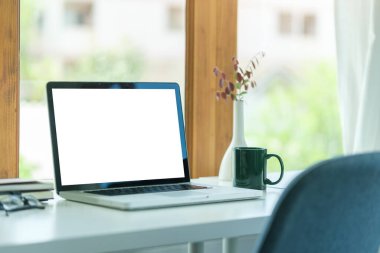 Computer laptop with empty screen, coffee cup, and potted plant on table. Home office.
