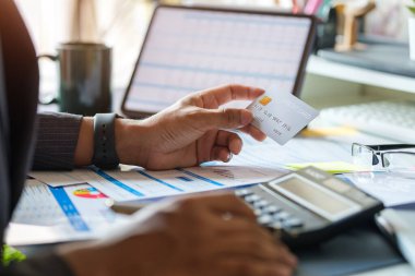 Young asian man holding credit card and using calculator. Online shopping, e-commerce, internet banking concept.	