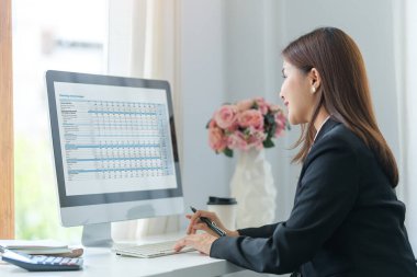 İş kadını bilgisayar monitöründe finansal veri satış grafikleriyle çalışıyor.